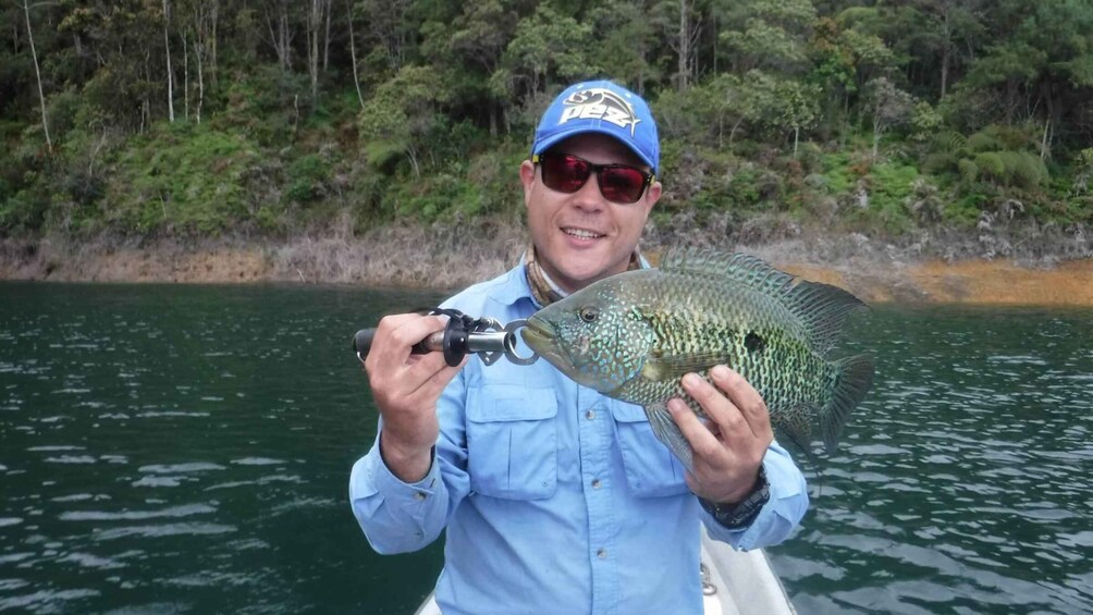 A person holding a fish with a fishing rod. 4