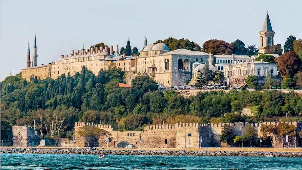 A historic cityscape with a prominent castle, domed buildings, and minarets. 1