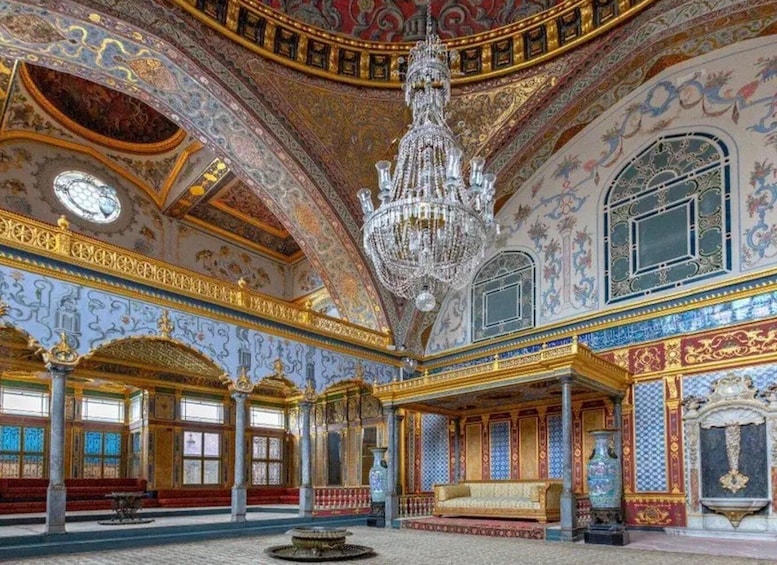 An opulent room with ornate decorations, a large chandelier, and a patterned floor. 3
