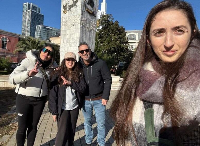A group of people posing in front of a monument with a clock tower and modern buildings in the background. 5