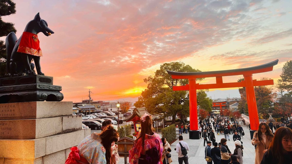 A sunset with a red torii gate and a statue of a dog in a park. 5