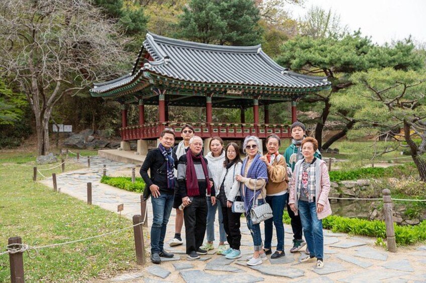 Un groupe de personnes se tient devant un pavillon coréen traditionnel dans un parc. 1