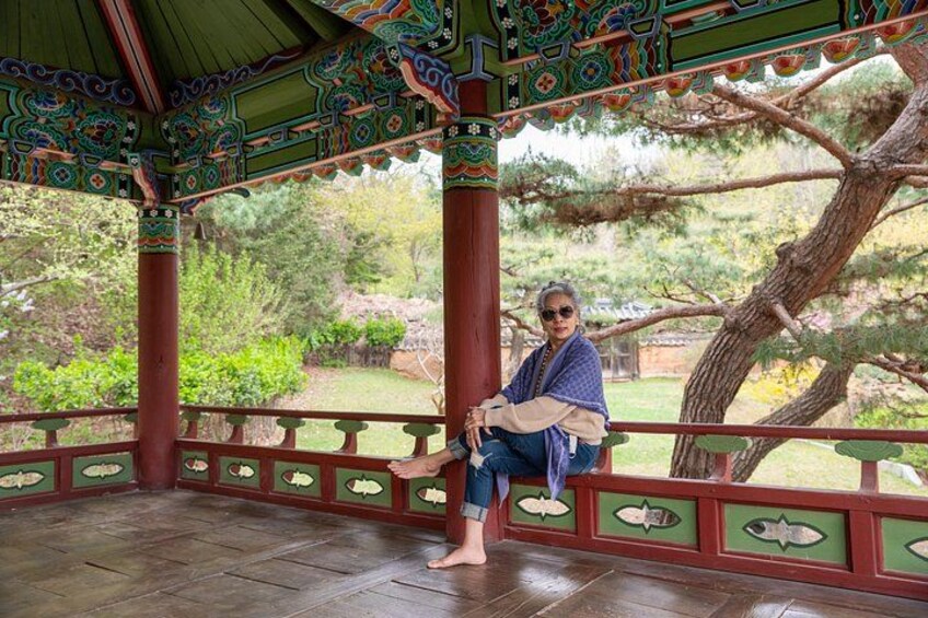 Une personne assise sur un banc en bois dans un belvédère aux motifs complexes. 2