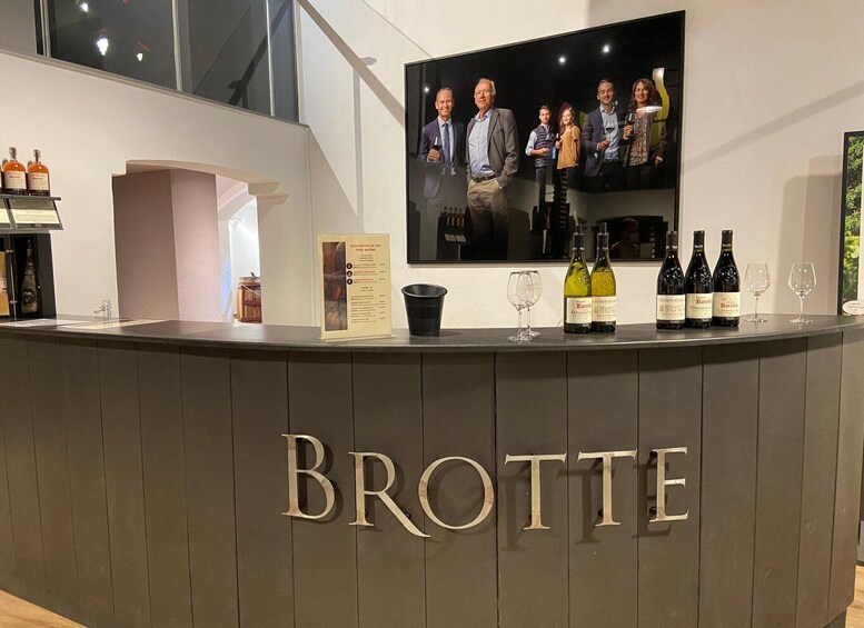 A bar counter with the name 'BROTTE' and several bottles of wine and glasses on it. 2