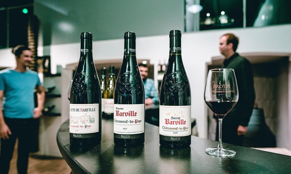 Three bottles of Barville wine and a glass of wine on a bar counter. 1