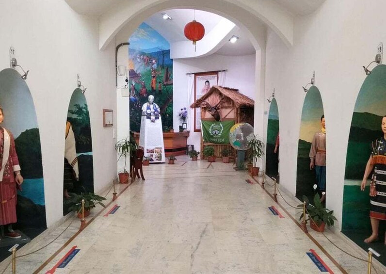 A museum corridor with murals, a Buddha statue, and potted plants. 2