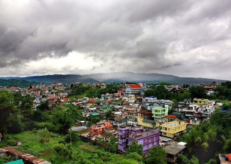 A densely populated urban area with colorful buildings, surrounded by lush greenery and hills in the background. 5