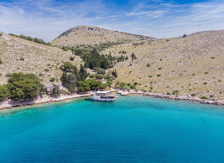 A boat anchored near a rocky coastline with a mountainous backdrop. 4