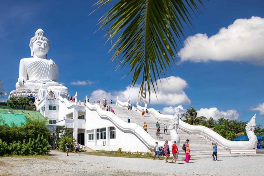 A large white Buddha statue, a white building with a curved roof, and a palm tree. 3