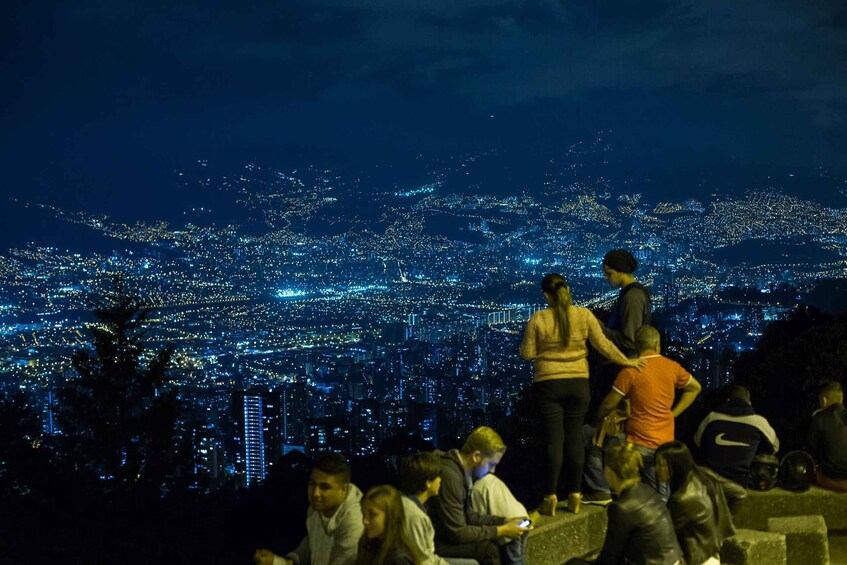 A nighttime cityscape with people observing the view. 1