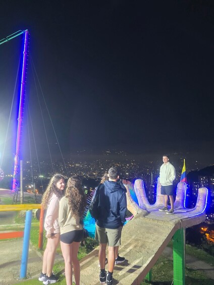 A group of people standing on a viewing platform overlooking a city at night. 2