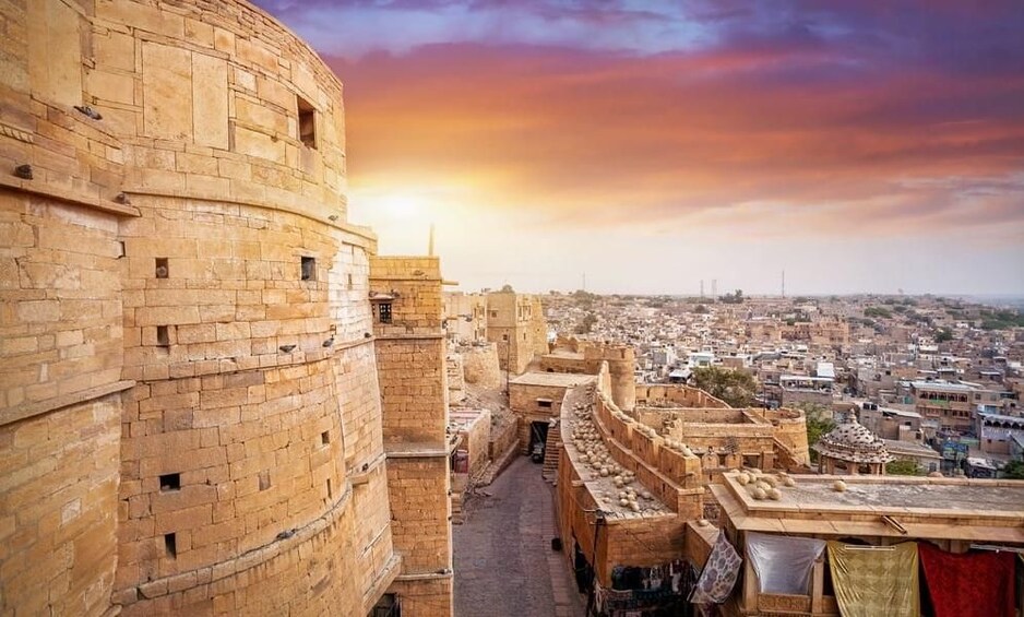 A historic fort with a view of a cityscape at sunset. 4