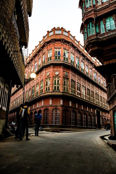 A historic red brick building with ornate balconies and green shutters. 2