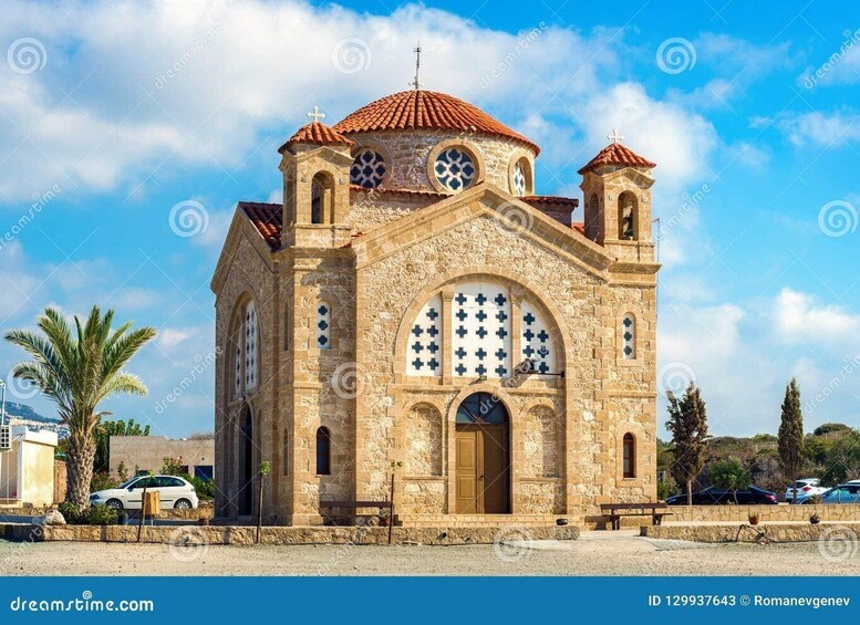 A stone church with a red-tiled roof, arched windows, and a bell tower. 5