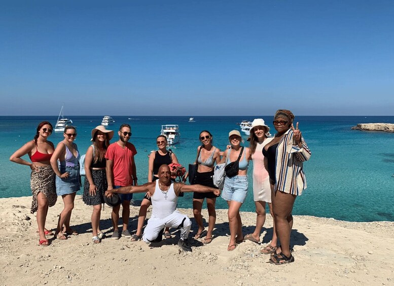 A group of people posing on a beach with boats in the background. 2