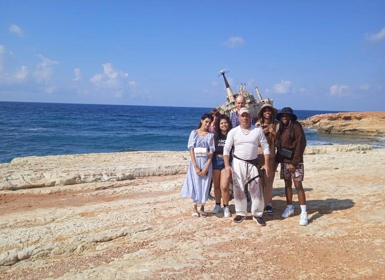A group of people standing on a rocky beach with the ocean in the background. 1