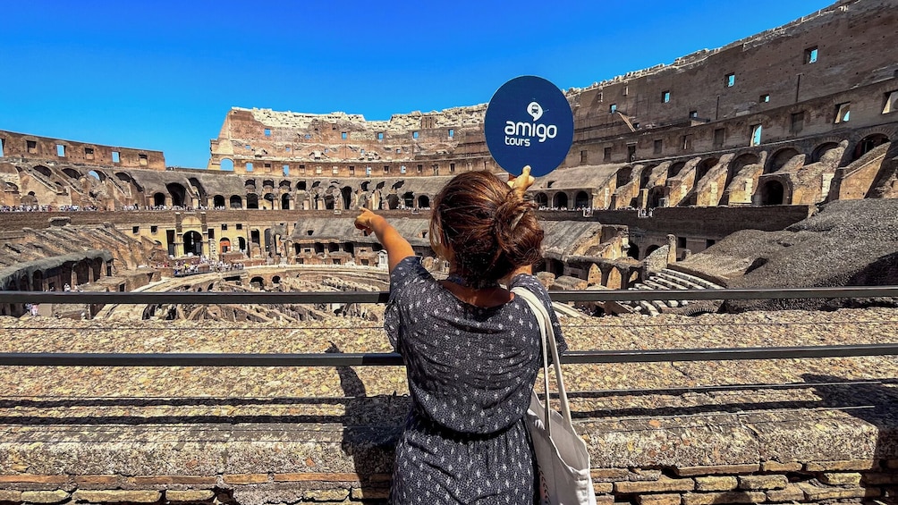 Una persona fotografiando el Coliseo, con un cartel de Amigo Tours al frente. 2