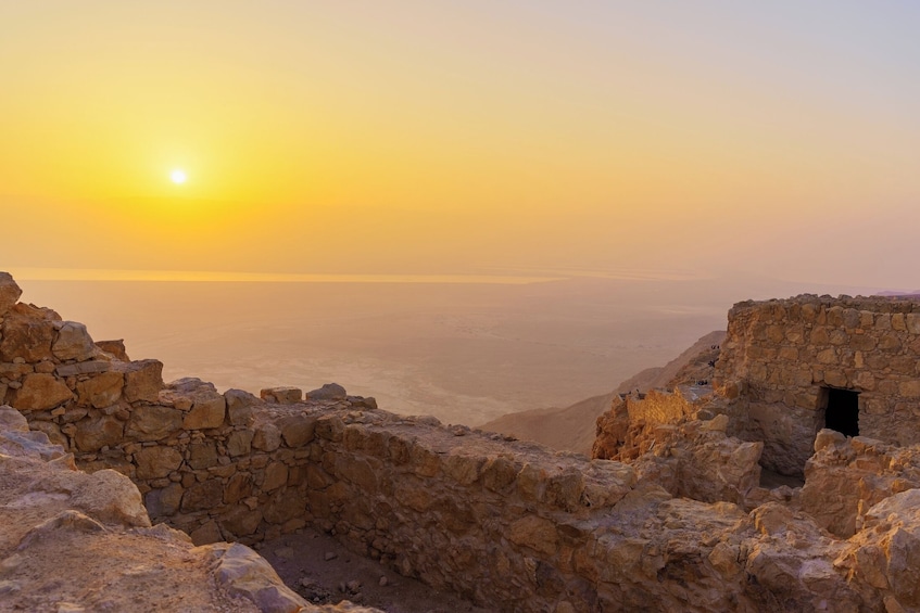 A stone ruin at sunset with a view of distant mountains. 1