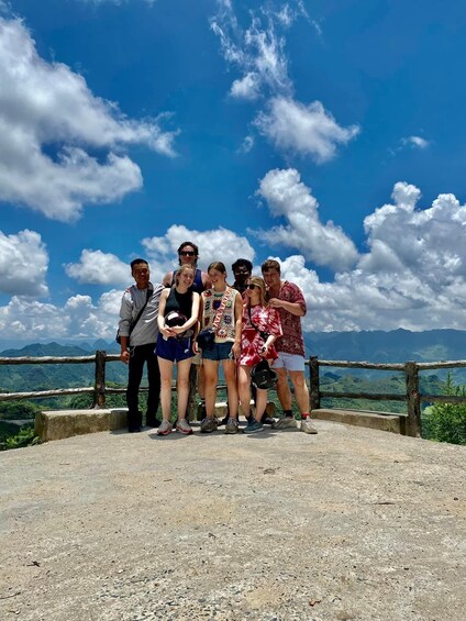 A group of people standing on a concrete platform with a scenic mountain view in the background. 1