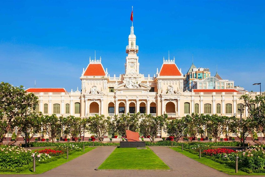A grand building with a clock tower, red roofs, and a flag. 1