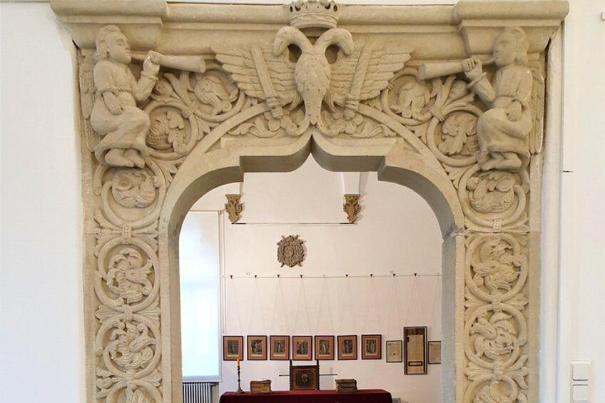 Un portal ornamentado con intrincadas tallas y un escudo heráldico en su parte superior. 2