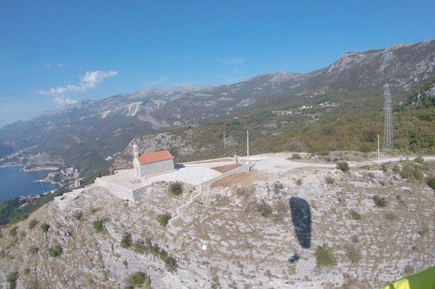 Un paisaje montañoso con un edificio pequeño, cielo despejado y una masa de agua distante. 5