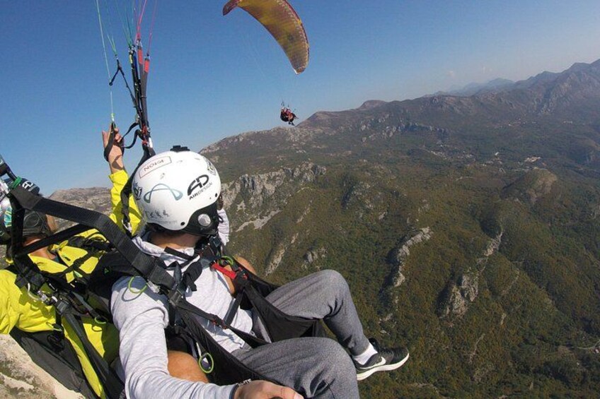 Una persona practica parapente con un paisaje montañoso al fondo. 3