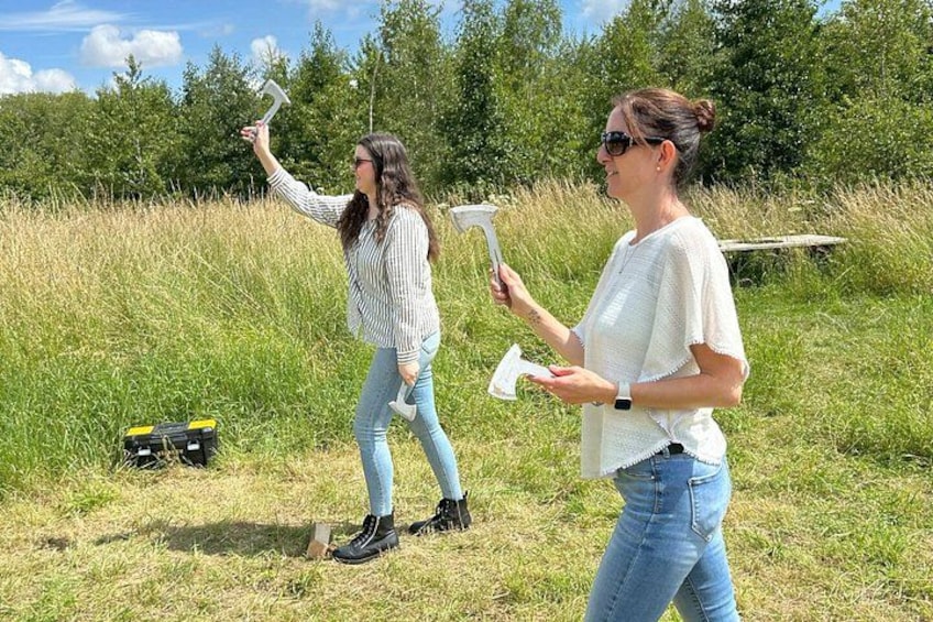 Two people in a grassy field holding objects, with trees and a clear sky in the background. 3