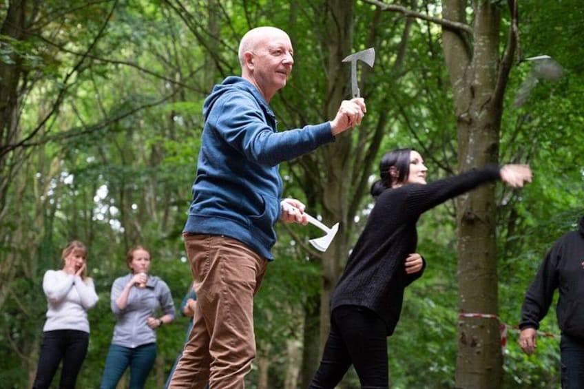 A group of people in a forested area, some holding axes. 4