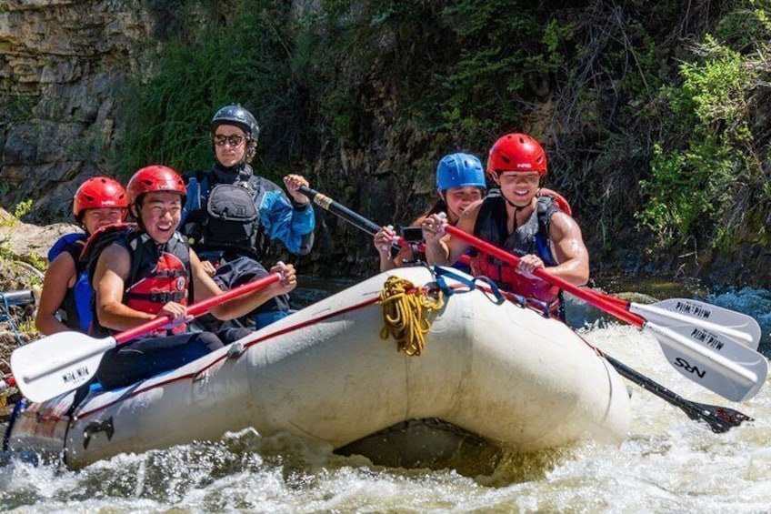 Un groupe de personnes à bord d’un radeau gonflable blanc navigue sur une rivière aux courants rapides. 1