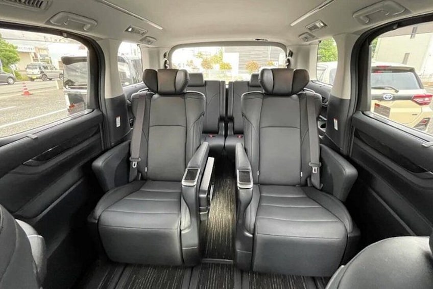 A vehicle interior with black leather seats, a central console, and a window view of the outside. 2