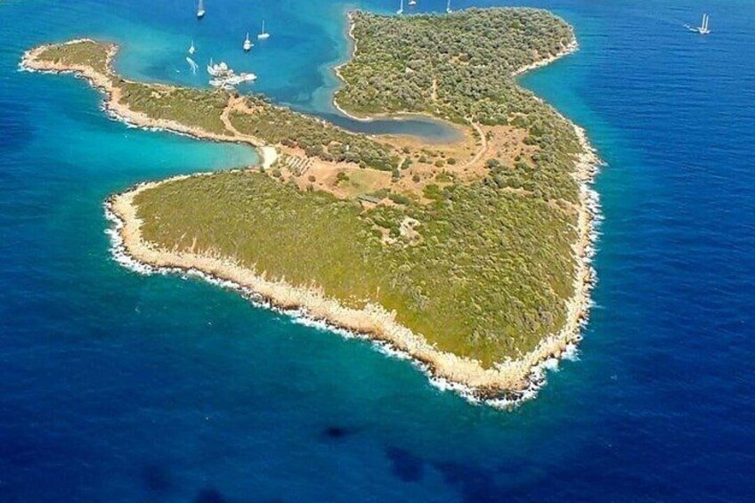 An aerial view of a heart-shaped island with clear blue waters, surrounded by smaller islets and boats. 4