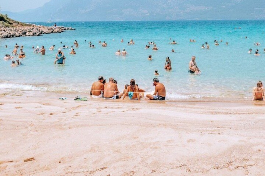 A crowded beach with people swimming and relaxing in the water. 1
