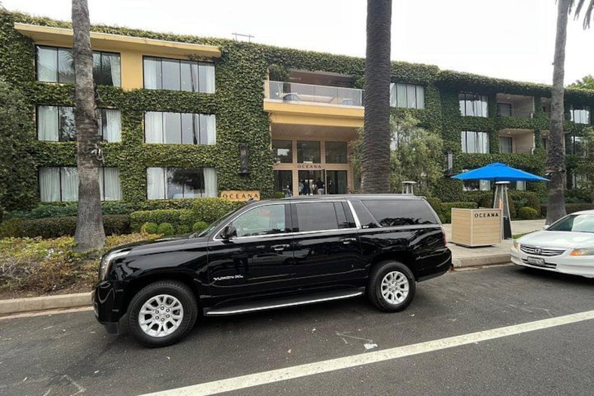 A black SUV parked on a street with a building in the background. 2
