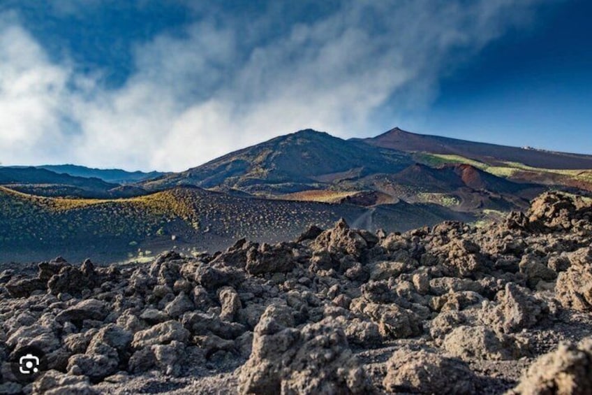 A volcanic landscape with rugged terrain and a mountain in the background. 2
