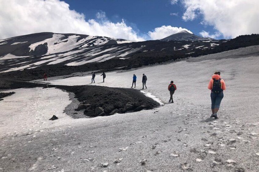 A group of hikers on a glacier with snow-covered mountains in the background. 1
