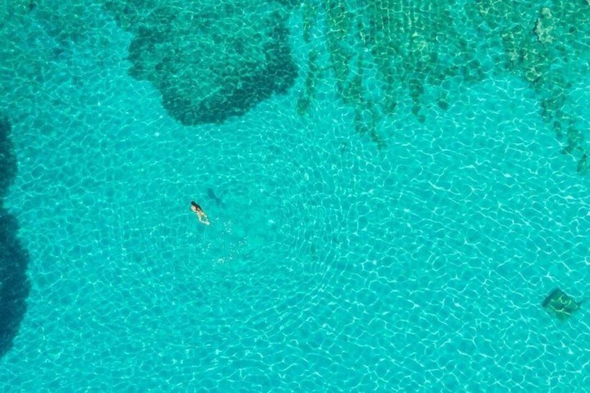 A clear turquoise sea with a small boat in the distance. 5