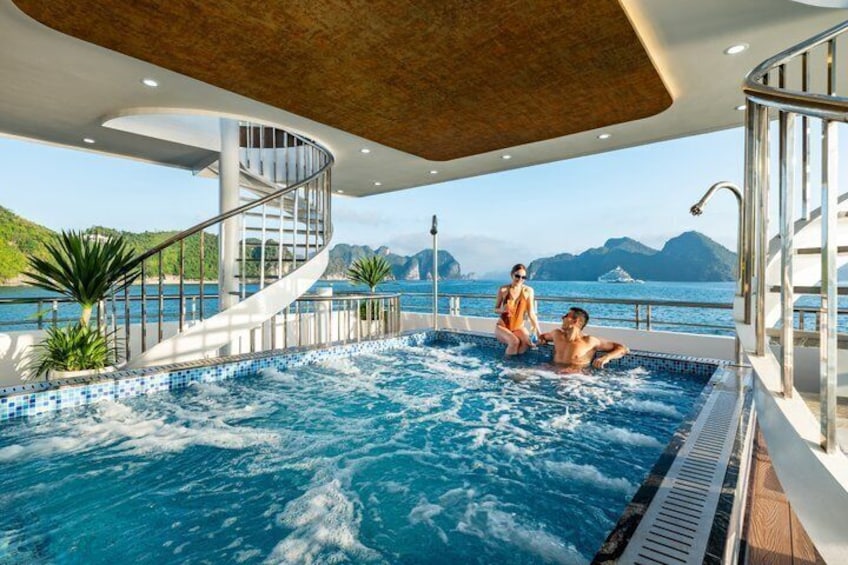 A hot tub on a cruise ship with a view of the sea and mountains. 4