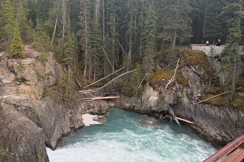 Une rivière qui traverse un défilé boisé, avec des falaises rocheuses et un pont en bois. 5