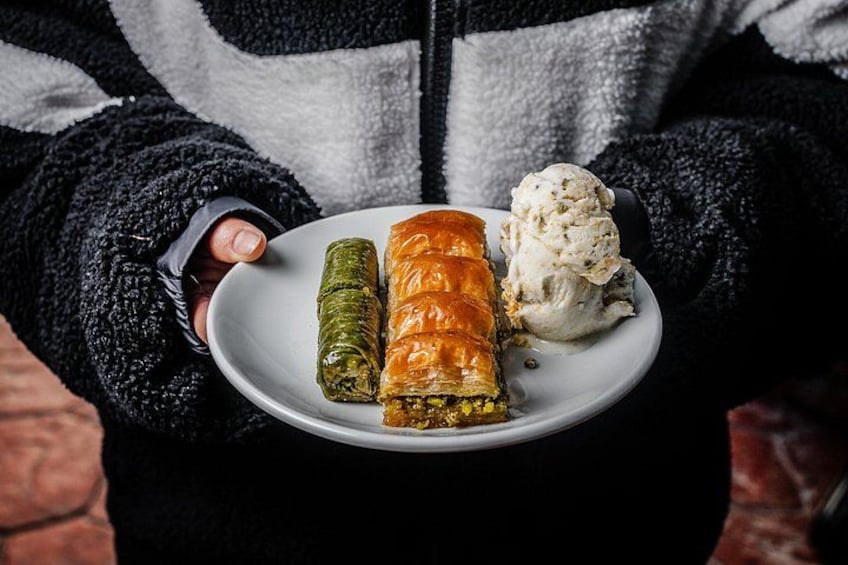 En person holder en tallerken med dolmades og en portion is. 2