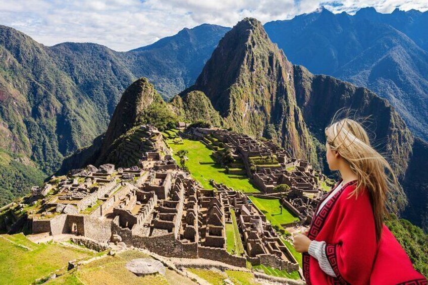 Machu Picchu ruins with Incan architecture, steep mountain backdrop, and a person in red. 1
