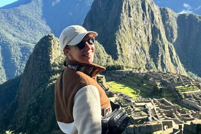 A person standing in front of Machu Picchu with the ruins of the ancient Incan city in the background. 5