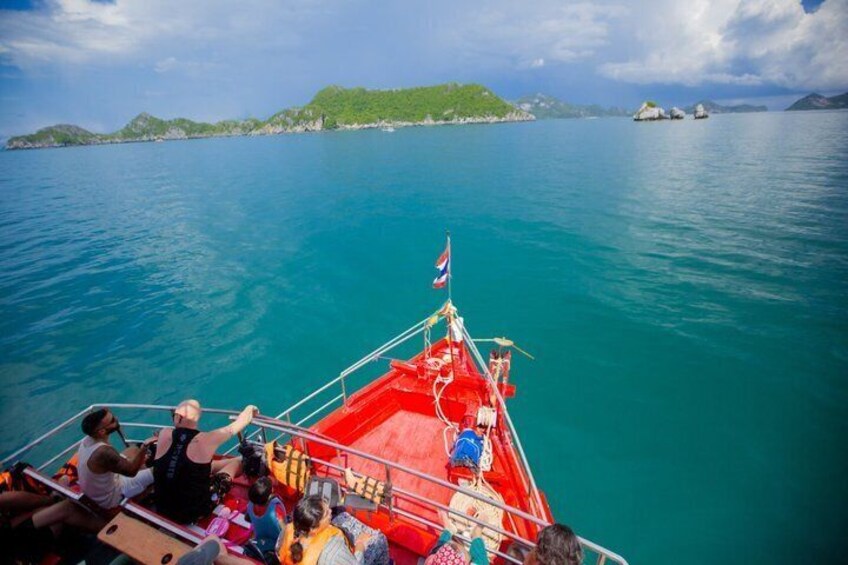 Un bateau rouge transportant des passagers, un drapeau, et une mer d’un bleu limpide avec une terre visible au loin. 4