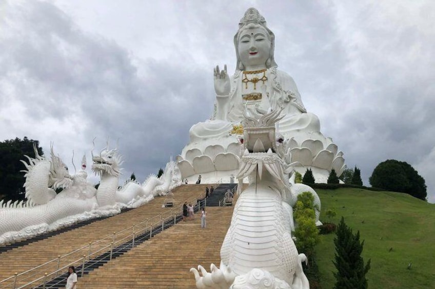 A large white Buddha statue with a dragon in front, surrounded by smaller dragon statues. 1