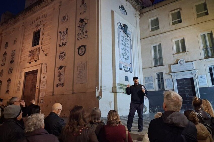 A person giving a speech outdoors in front of a building with historical plaques. 5