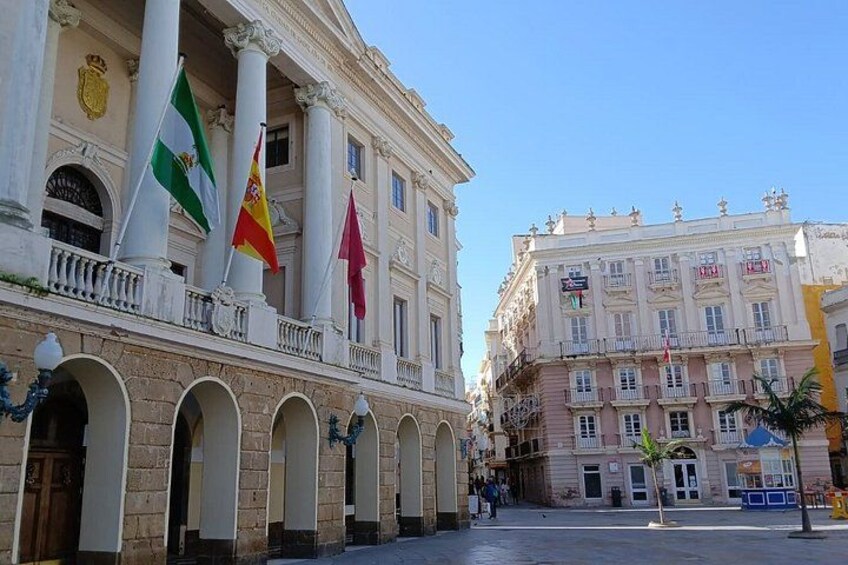 A historic building with columns, flags, and a clear blue sky. 3