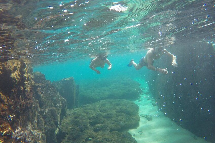 Zwei Personen schwimmen unter Wasser in der Nähe von Felsformationen. 2