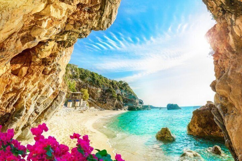 Un paysage côtier caractérisé par une falaise rocheuse, une mer turquoise aux eaux limpides et une plage de sable. 3