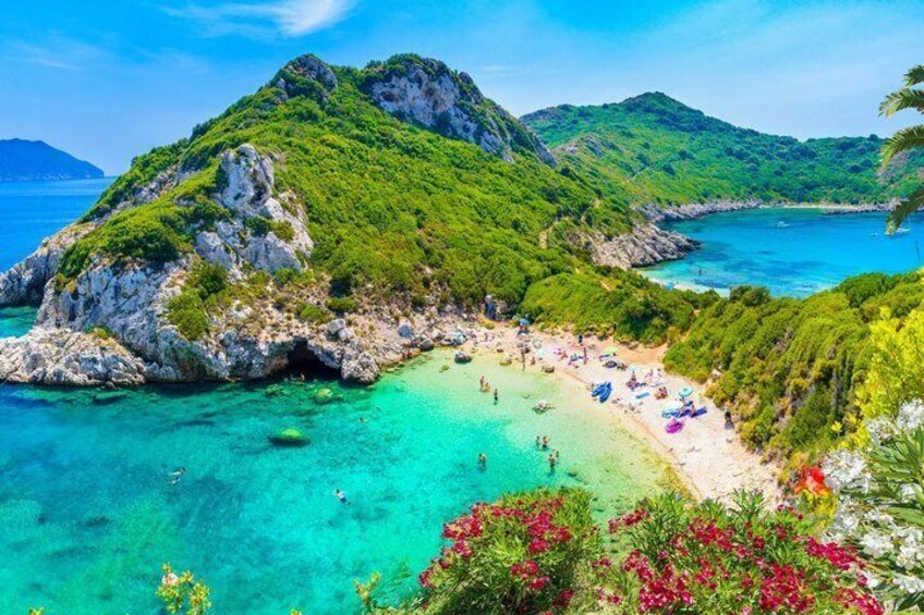 Un paysage côtier avec une plage, des eaux turquoise et limpides, et des collines verdoyantes. 2