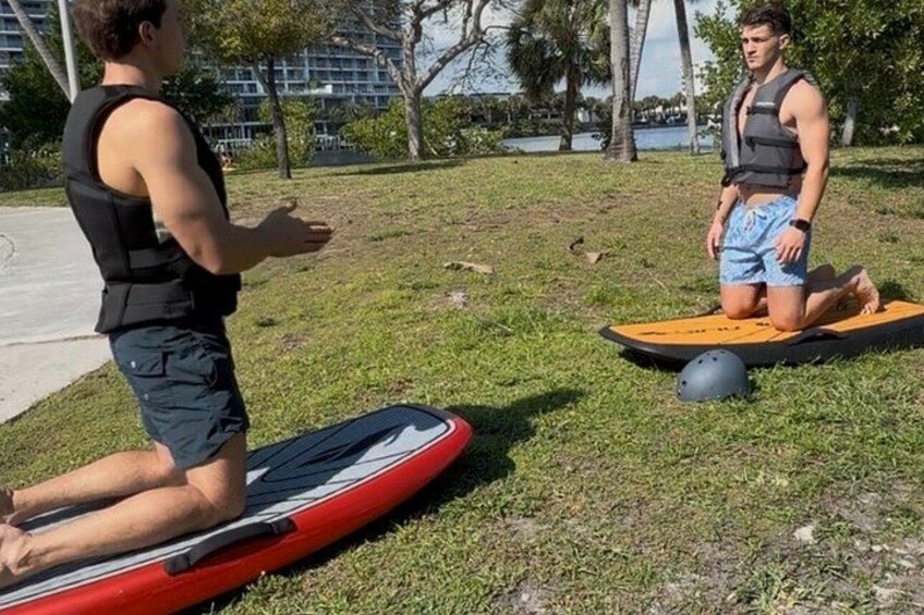 Deux personnes se trouvent sur une pelouse, avec une planche de surf rouge et une planche de surf jaune, et un casque est posé par terre. 1